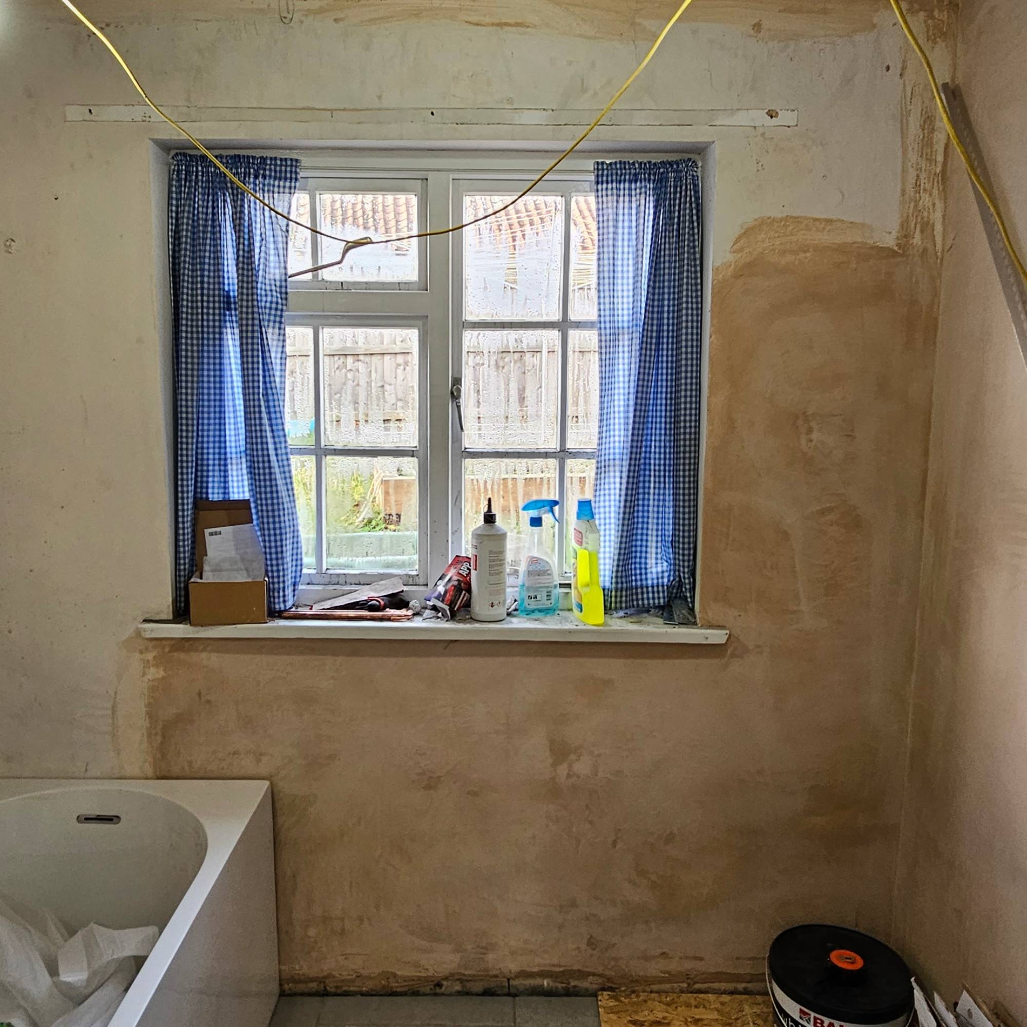 white cottage windows with blue curtains in bathroom renovation