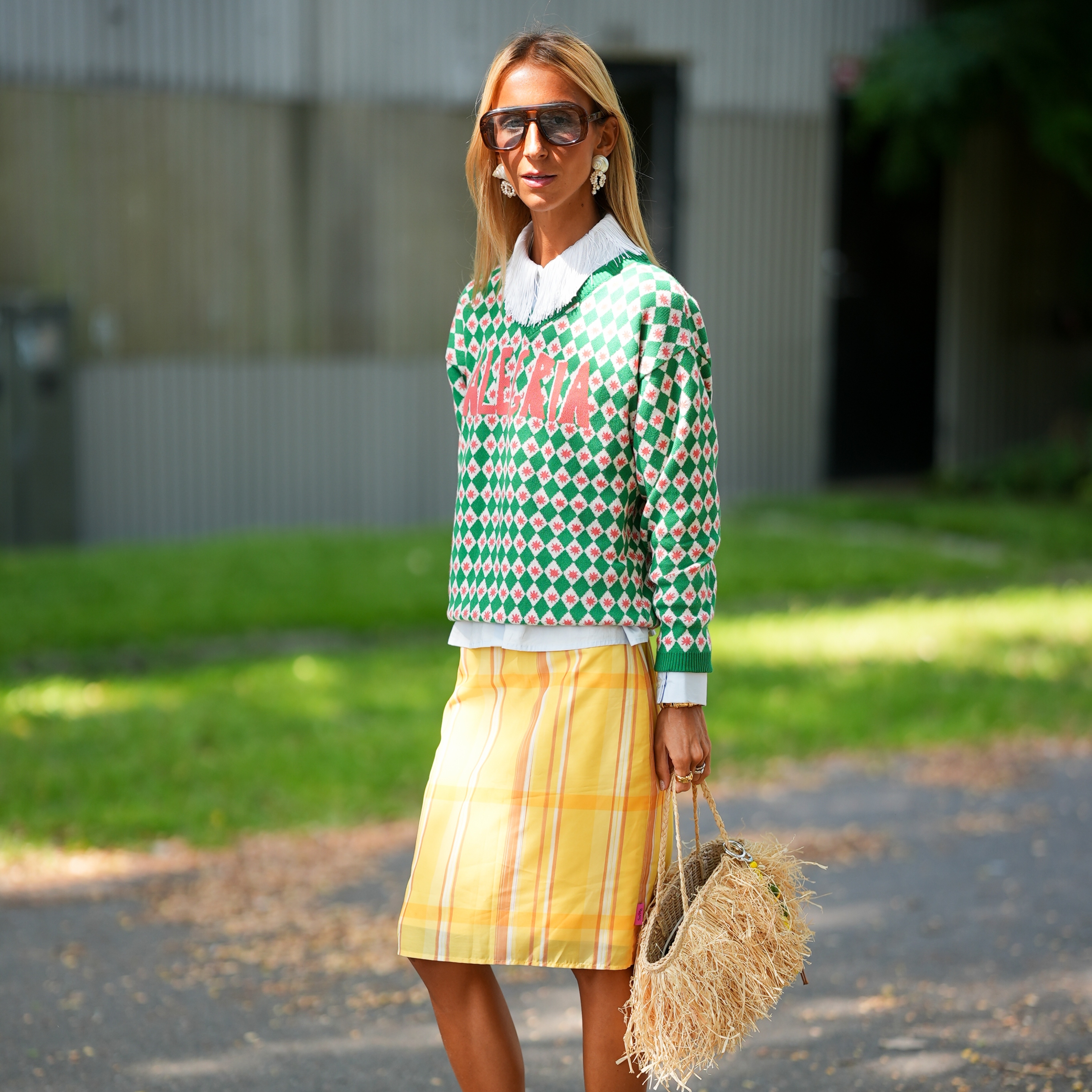 Guiomar Machaz is seen wearing a green and white patterned knit sweater with Victoria lettering layered over a white shirt with a pointed collar