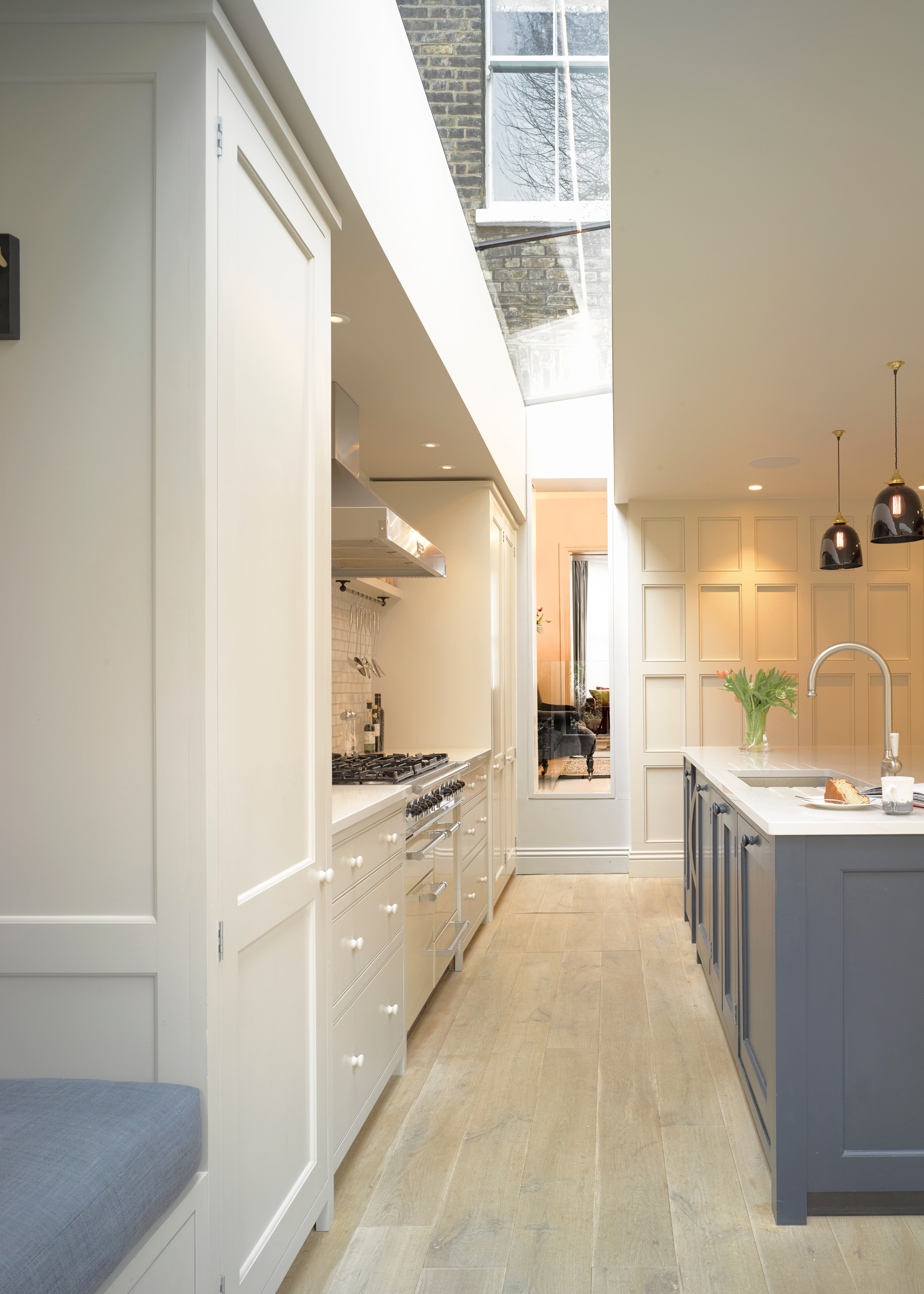 A traditional kitchen with a floor to ceiling strip of glass that comes along the length of the kitchen as a roof