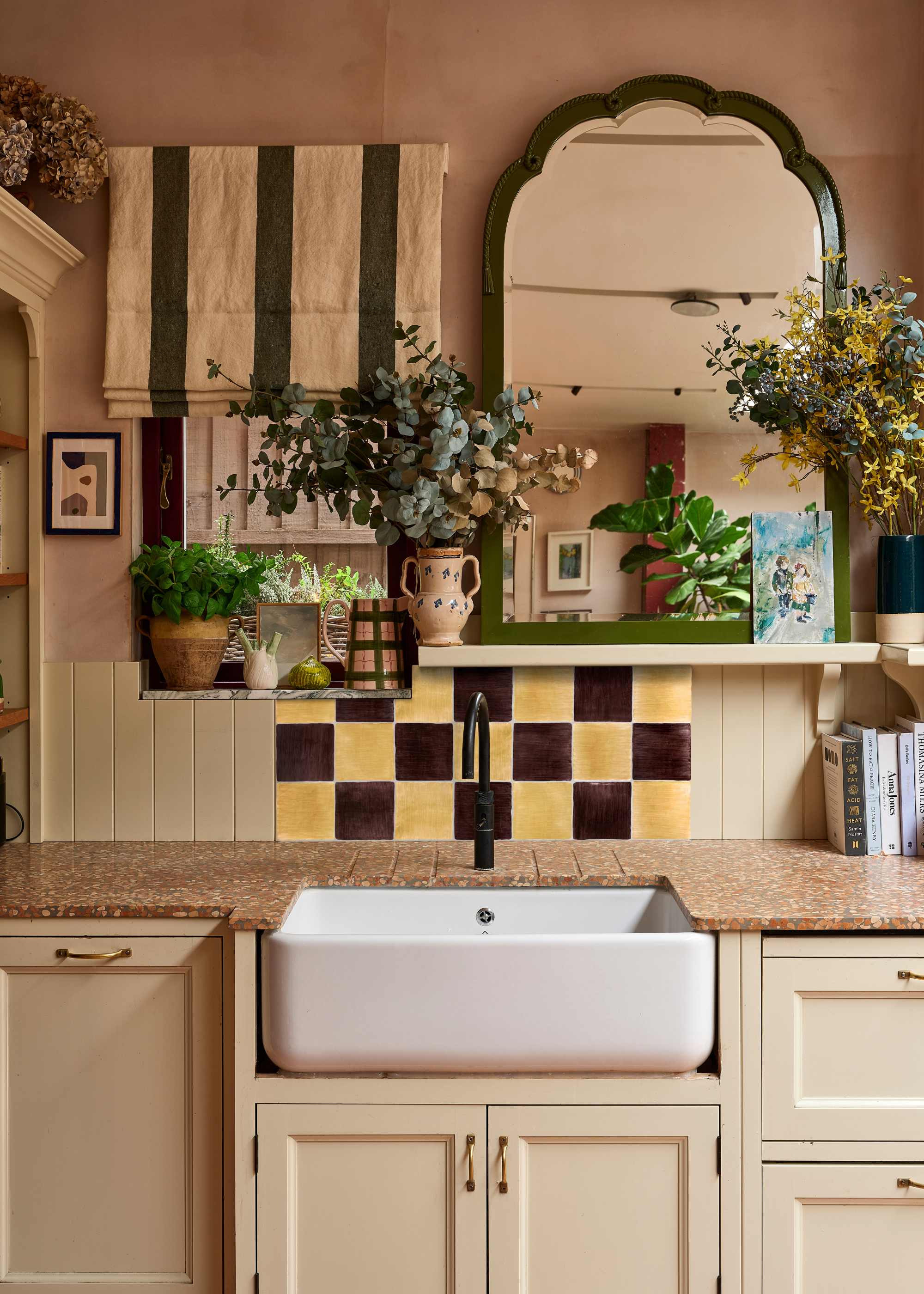 a country style sink on pale yellow cabinetry with eclectic styling and a yellow and brown gingham tile backsplash behind