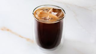 A black iced coffee on a marble countertop