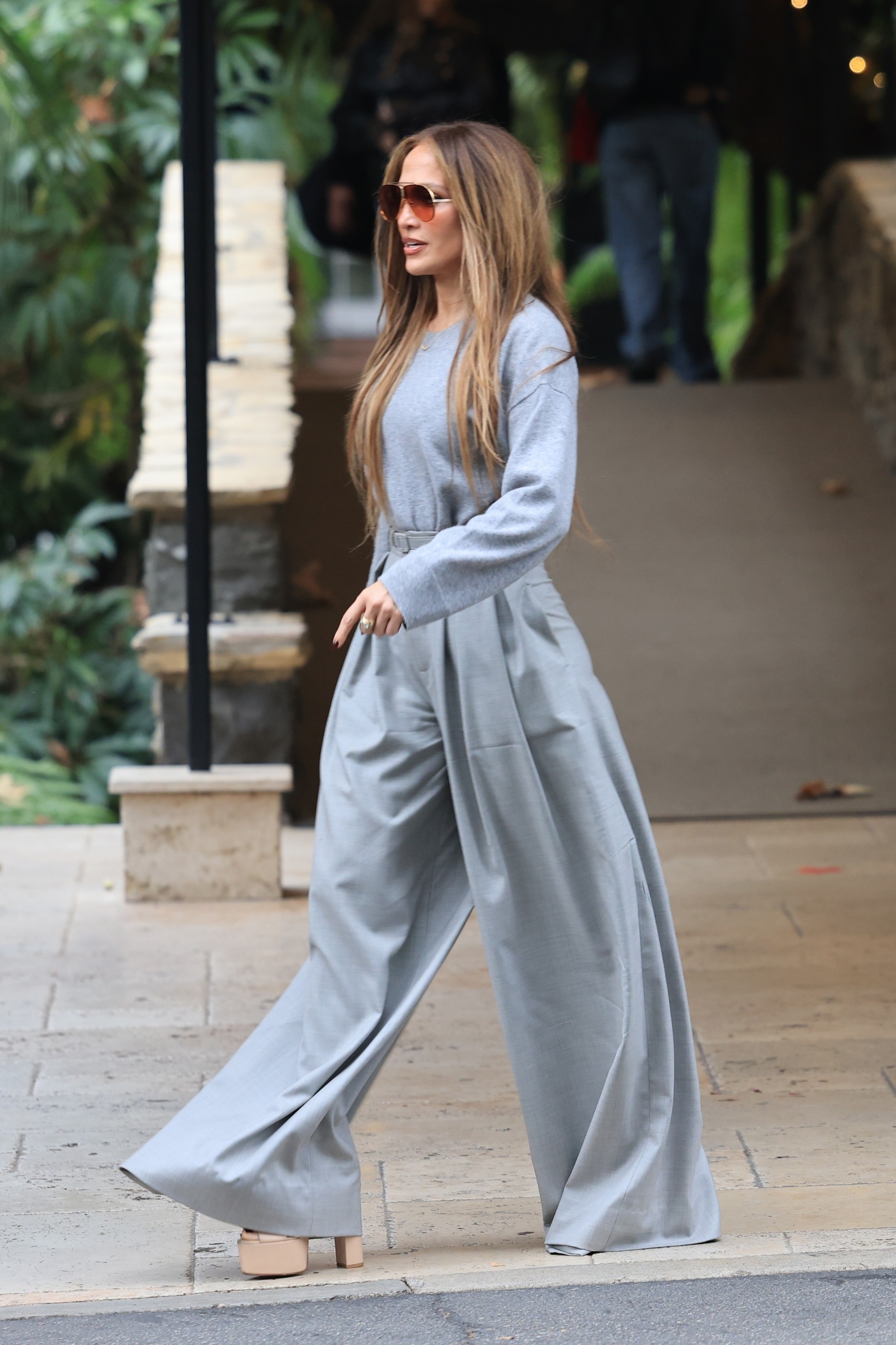 Jennifer Lopez wears gray wide-leg pants with platform heels