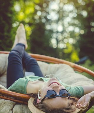 girl laying in hammock in garden listening to music