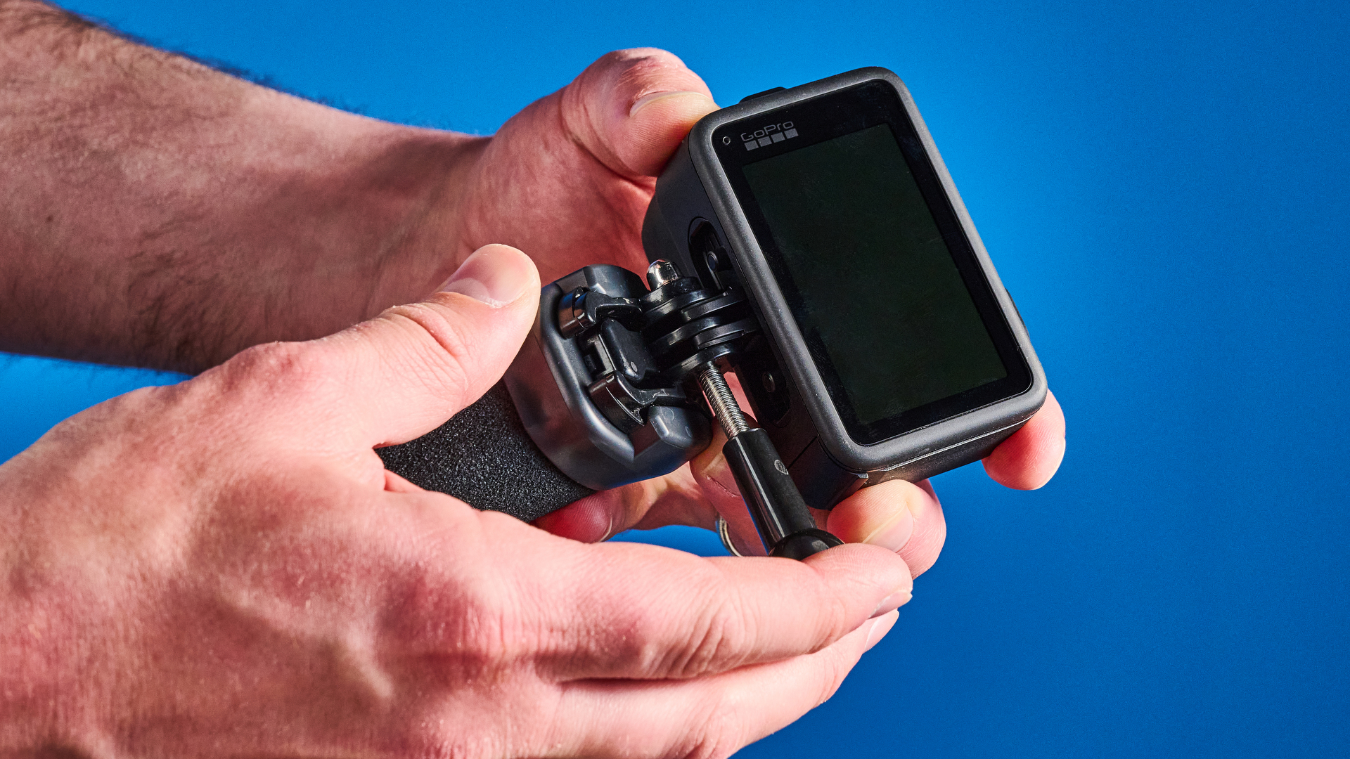 The GoPro Mission 1 Pro in hand against a blue background