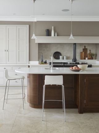 Kitchen with white cabinets and wood island with white counter, neutral walls and tile floor