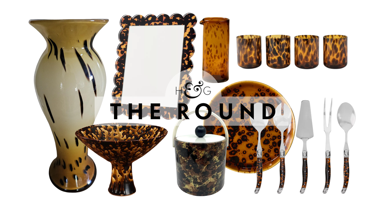 Tortoiseshell decor, including a vintage vase, pedestal bowl, tabletop mirror, antique ice bucket, handblown water pitcher, tumbler set, dinner plate, and flatware, pictured against a white background