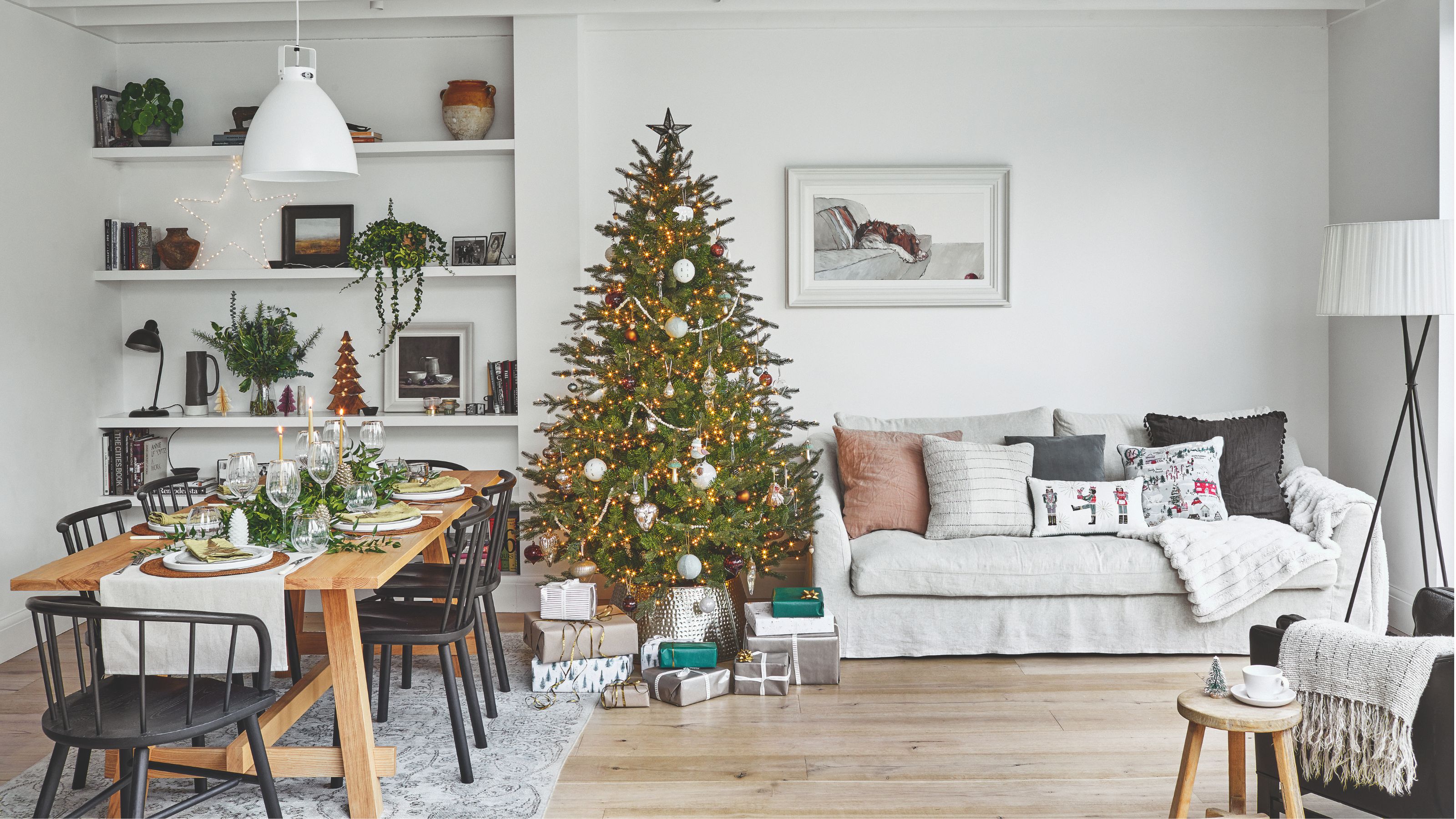 Open plan living room/diner with a christmas tree between the dining room table and a grey sofa
