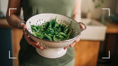 Woman holding a colander full of leafy green vegetables, an example of what to eat when you feel tired