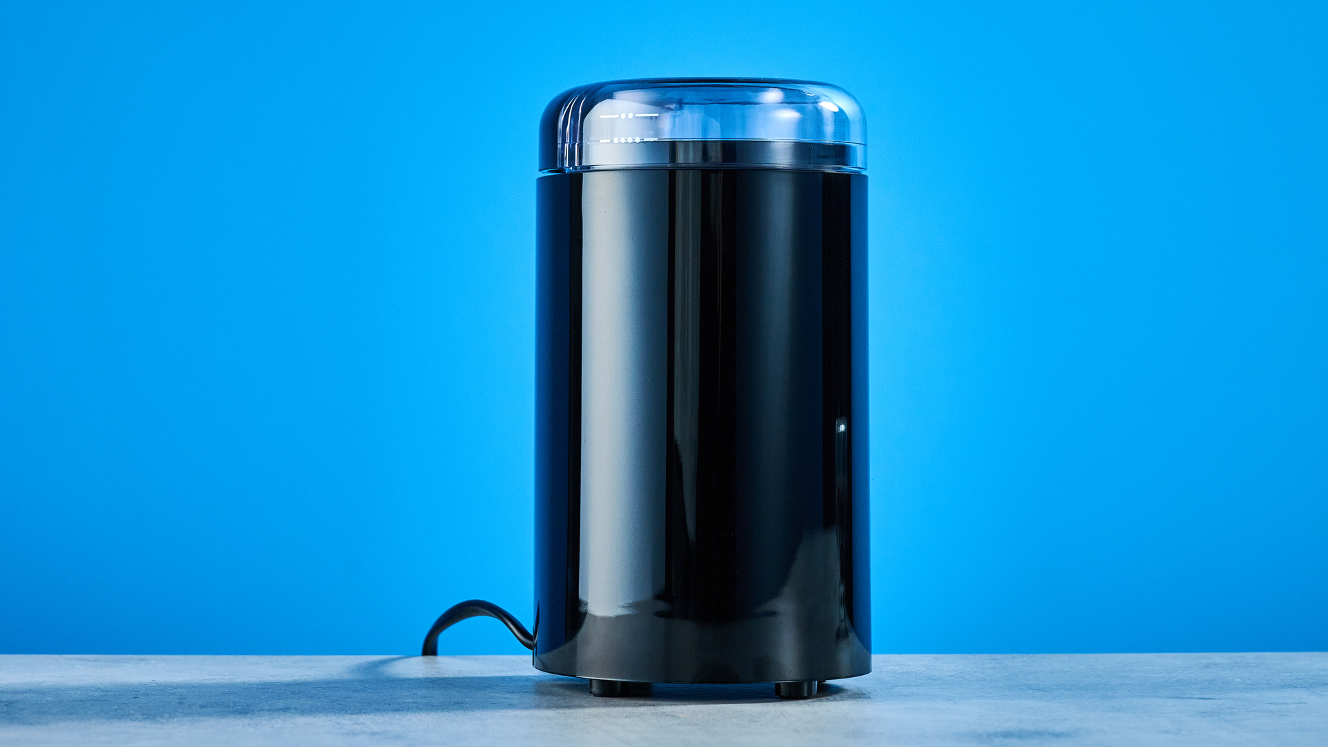 the cuisinart coffee grinder photographed against a blue background showing its blades and canister