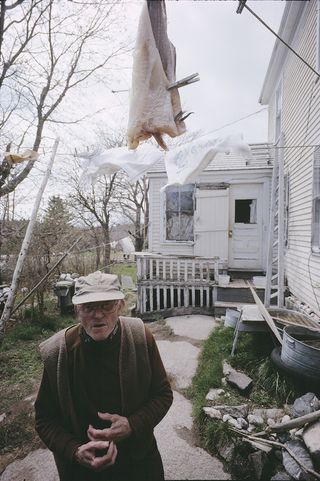 an elderly individual in a garden under a fish drying on a clothes line