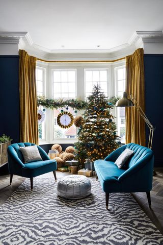 Christmas tree in a bay window. The living room is blue and yellow with a blue love-seat and matching accent chair