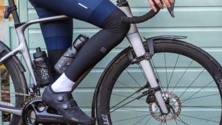 A cyclist wearing blue shorts and black leg warmers 