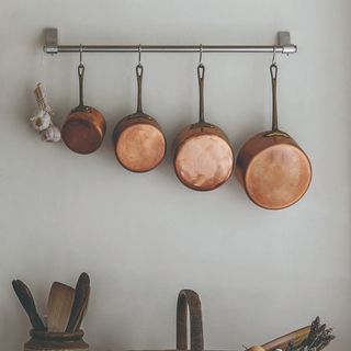 Copper pans hanging on a kitchen wall