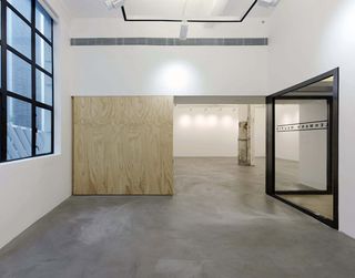 The new gallery incorporates a sliding plywood wall, which separates a large exhibition space from a smaller one.