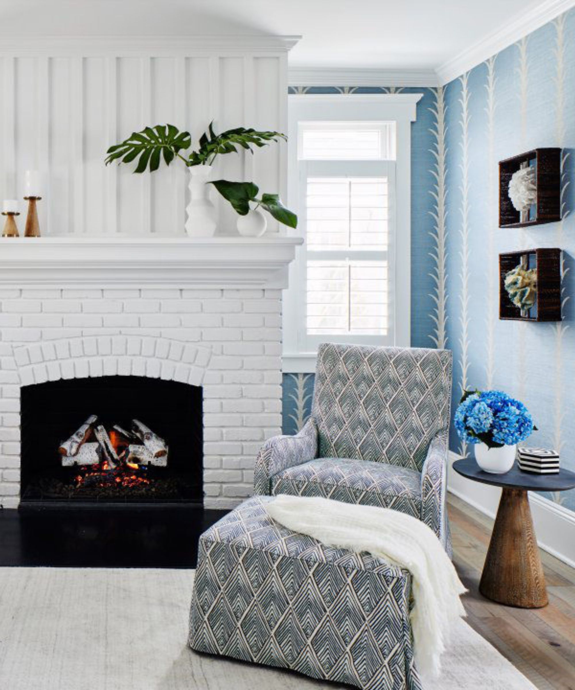 white coastal living room with blue patterned wallpaper and a large fireplace