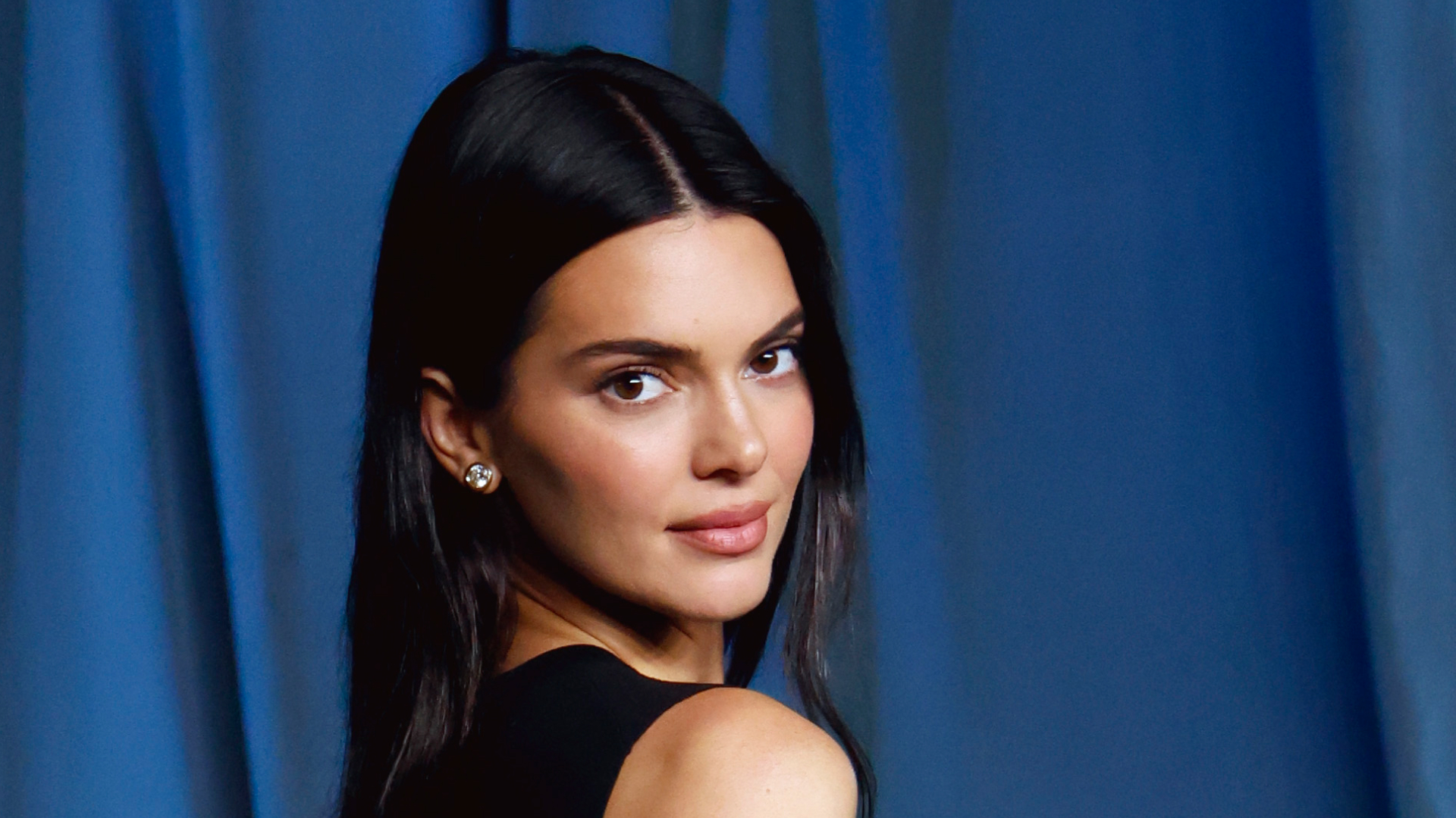 A woman with dark hair looking over her and smiling at the camera
