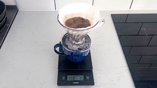 a black coffee scale by Hario is photographed in real-life usage in a kitchen