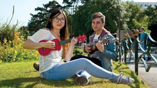 Couple in a park, both playing beginner ukuleles
