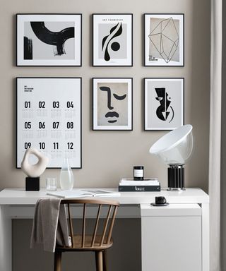 A neutral home office with white, black and taupe wall art as part of gallery wall