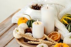 A selection of candles and miniature pumpkins on a small table