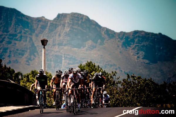 The peloton rides through Paarl with the mountains in the background.