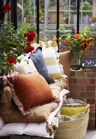 garden bench with cushions, basket with cushions, plants and flowers