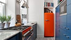 Color-pop galley kitchen with red fridge, fresh herbs, patterned floor tiles and natural daylight
