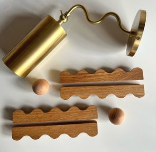 A brushed bronze sconce light and wavy wooden hardware for cabinet doors