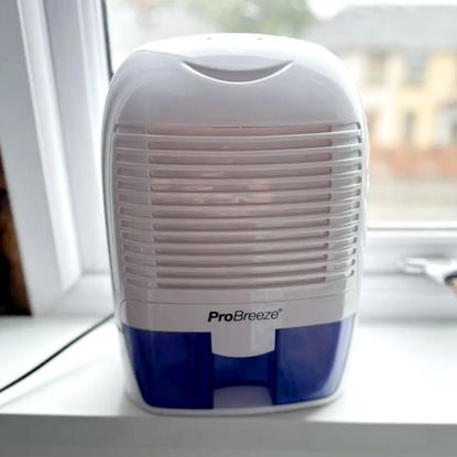 The white and purple ProBreeze 1500ml Mini dehumidifier on a white windowsill