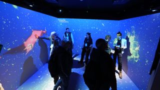 People inside a room projection mapped with content in vibrant blue and red.