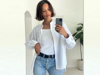 influencer Tylynn Nguyen posing for a mirror selfie wearing an open white button-down shirt, white T-shirt, black belt, and jeans