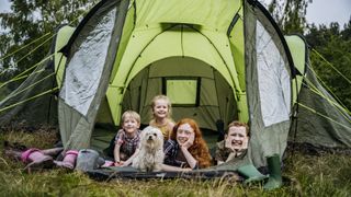 Children lying in tent with dogs, smiley