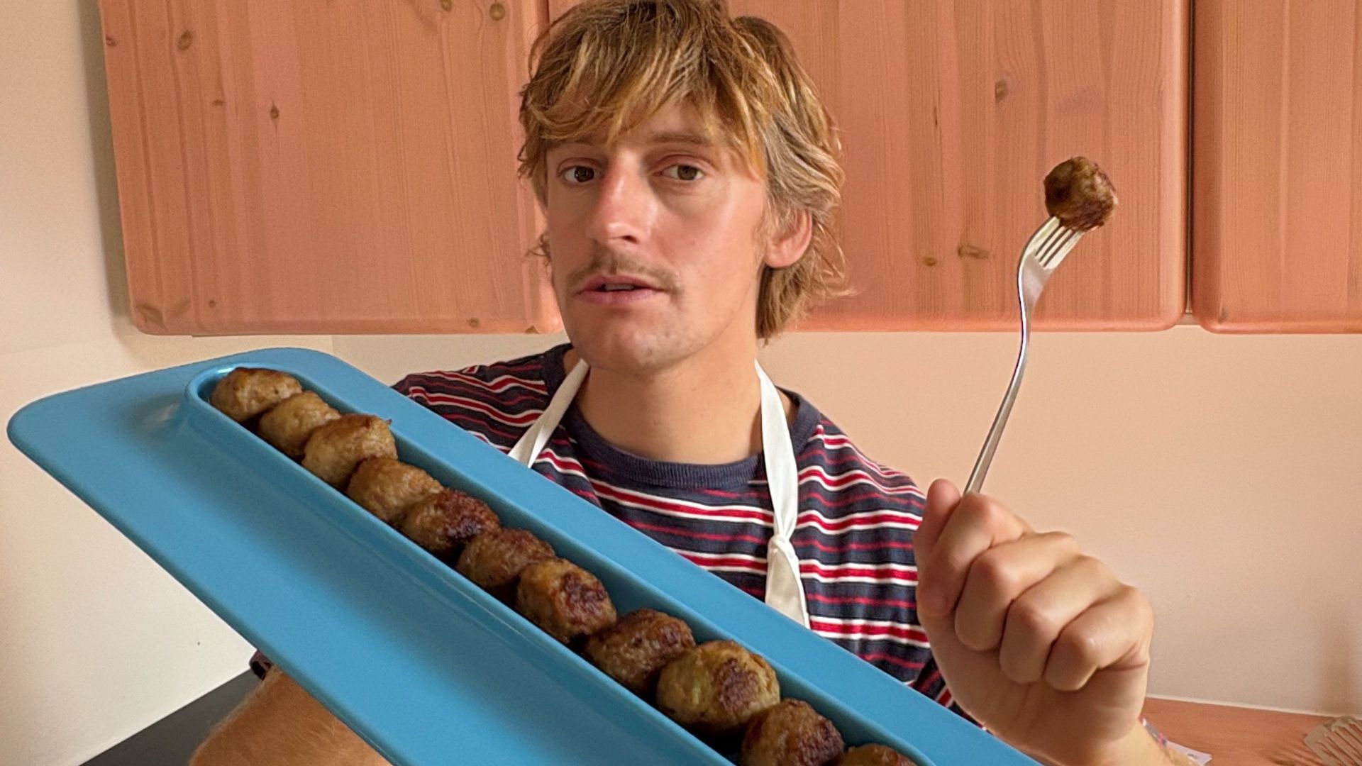 an image of Gustaf, the designer, holding the plate which is filled with meatballs