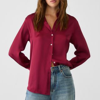 woman wearing a red silk shirt half untucked into jeans