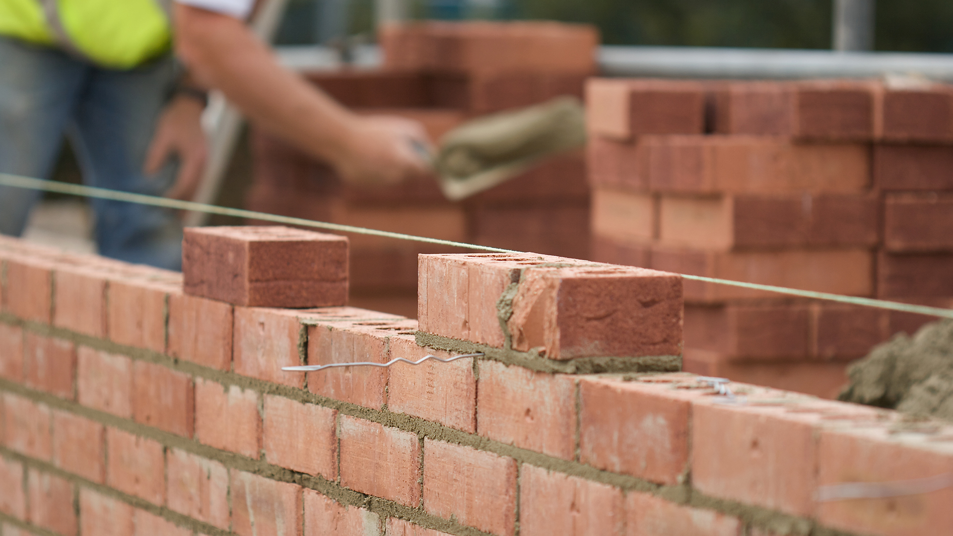 Builder laying bricks to build a wall