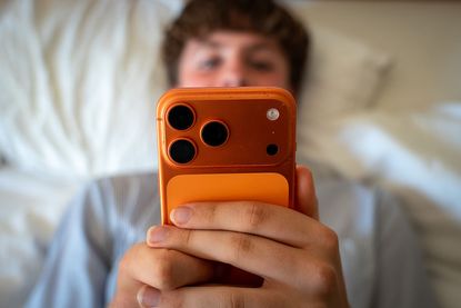 Social media ban: teenage boy looking at an iPhone
