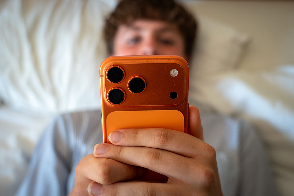 Social media ban: teenage boy looking at an iPhone