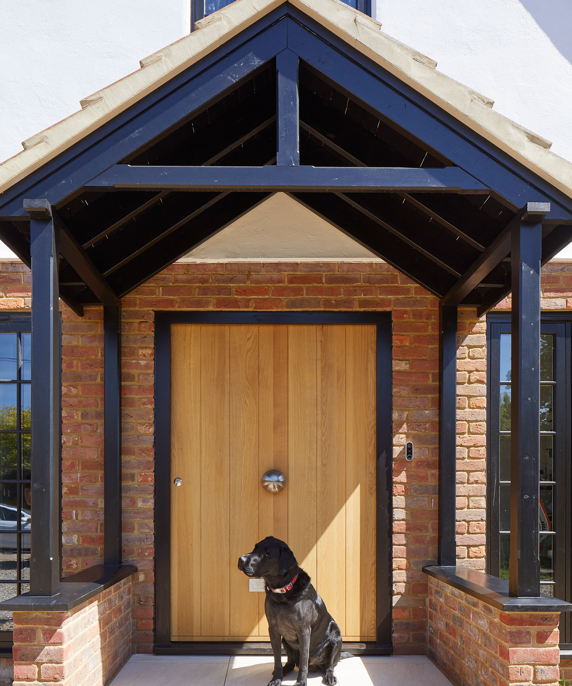 modern pitched roof porch with oak front door and black Labrador