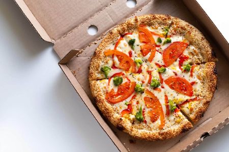 Italian pizza in a pizza box and for delivery, on a white background or table. Pizza Margarita with tomatoes and cheese and broccoli, without meat.