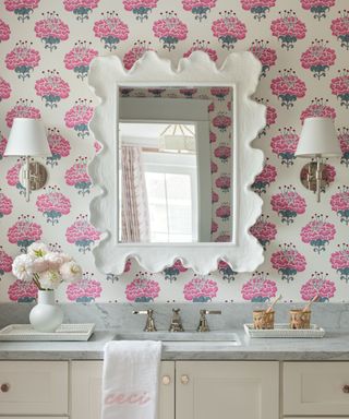 pink floral wallpaper in a bathroom with a marble vanity and a decorative large mirror