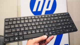 A person holding the EliteBoard G1a keyboard-PC with an HP logo in the background