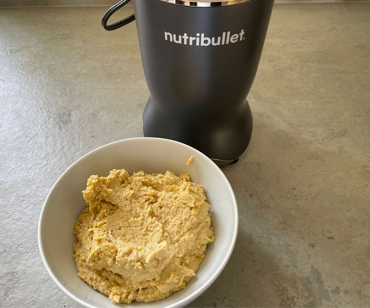 A bowl of hummus in front of the Nutribullet Ultra