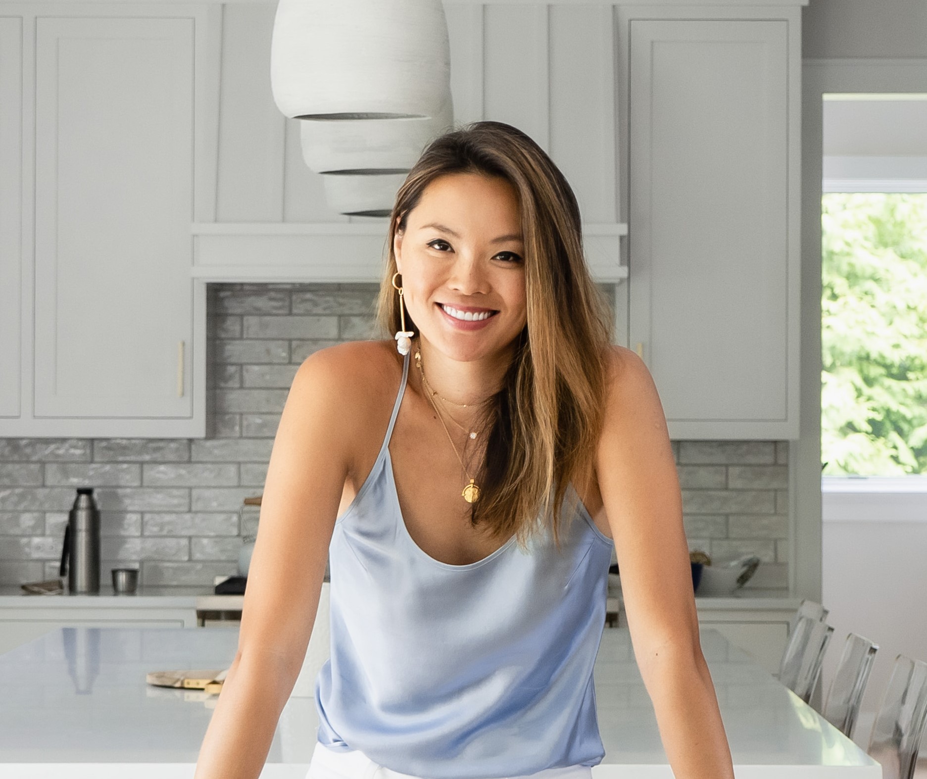 A picture of Kathy Kuo in a kitchen with a blue top on