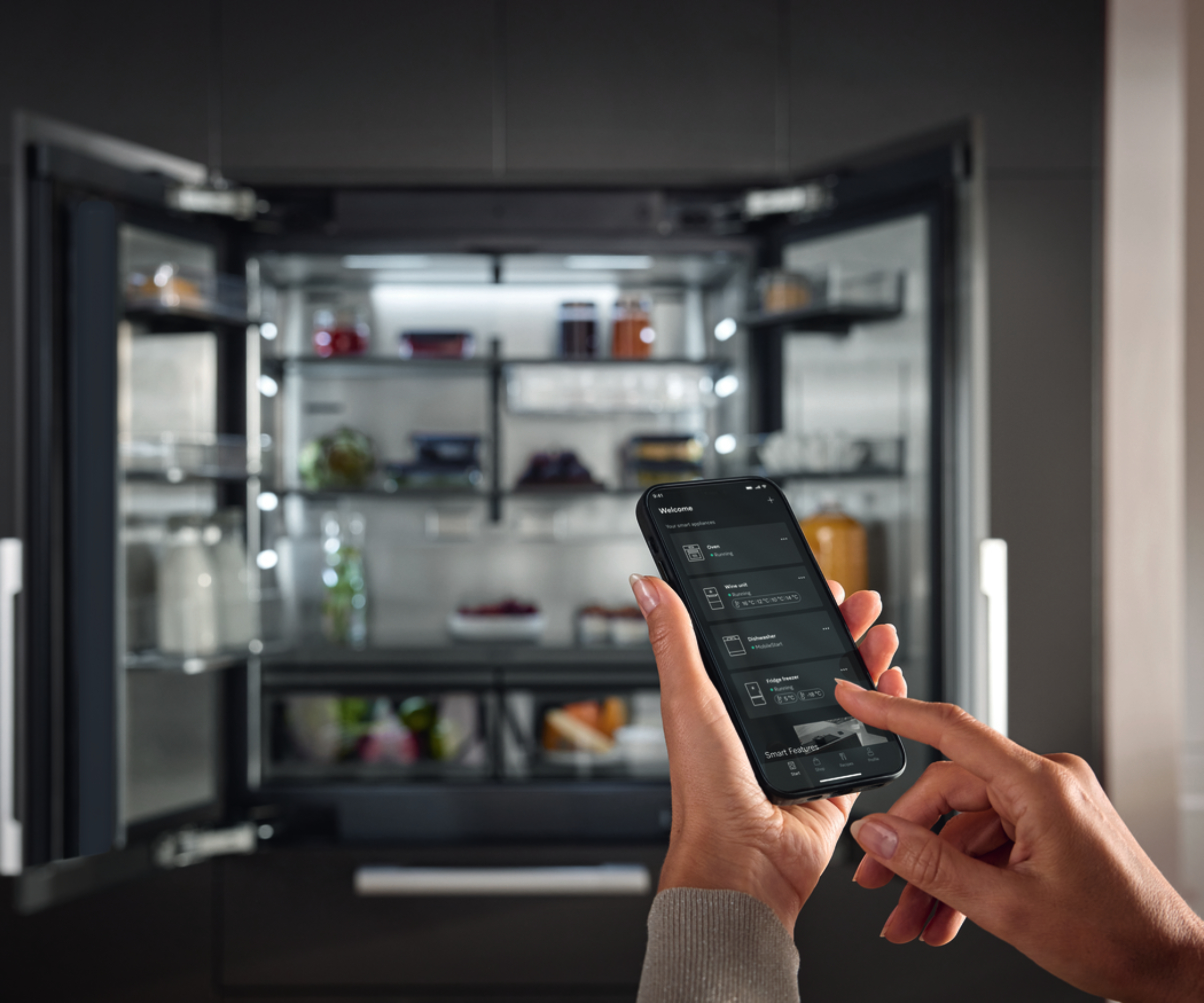 hands using app on phone with large fridge open in background