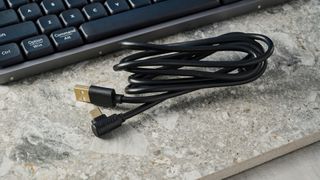 The Lofree Flow84 cables, on a stone surface with a blue wall in the background