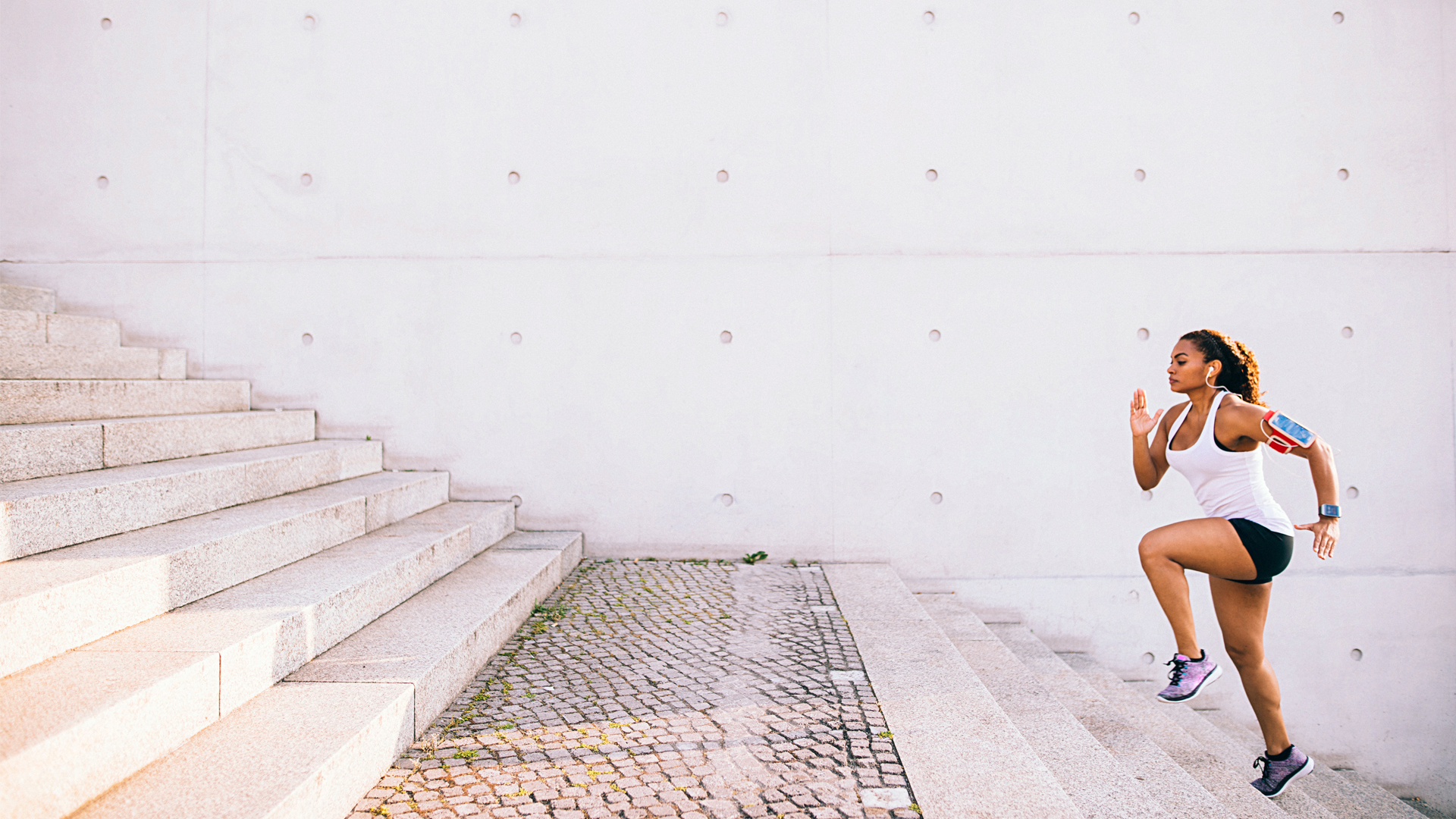 Image of woman running up a set of stairs wearing a fitness tracker