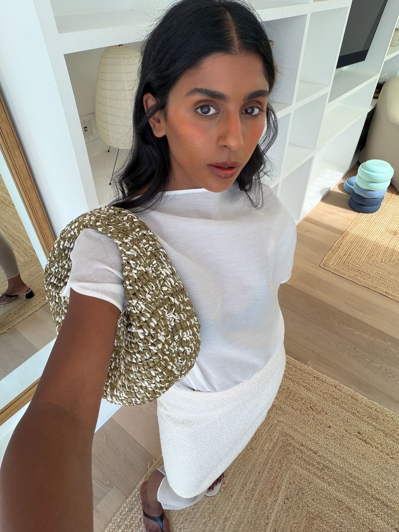 Monikh wears a white tee, white skirt, and green and white bag.