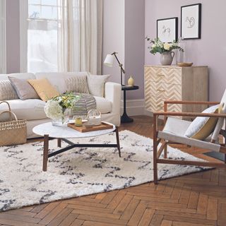 Living room with dark wood herringbone flooring, a coffee table and armchair.