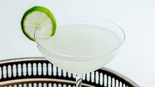 martini glass on a metal tray with a lime wheel garnish