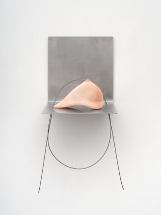 sculpture of a breast on a shelf in an art gallery